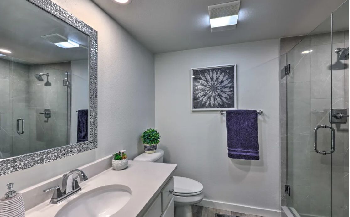 Un baño moderno con un espejo grande, un lavabo, un inodoro y una ducha.