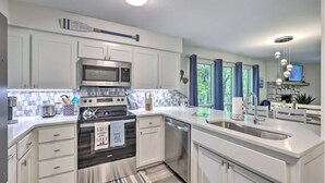Una cocina moderna con armarios blancos, electrodomésticos de acero inoxidable y una isla grande con un lavamanos.