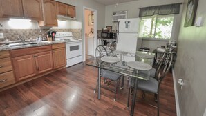A kitchen with wooden cabinets, a glass dining table, and a ceiling fan.