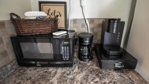 A kitchen with a microwave, coffee maker, and a basket on the counter.
