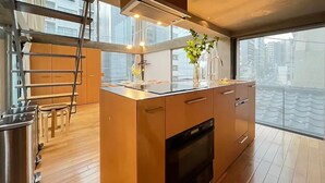 Una cocina moderna con una isla central, horno empotrado y ventana con vistas a la ciudad.