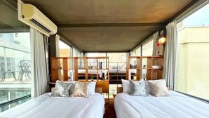 Habitación de hotel con dos camas, un ventanal grande y vistas al exterior.