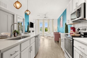 A modern kitchen with white cabinets, a large island, stainless steel appliances, and a view through the glass doors. - Chic 1-bedroom apartment in vibrant San Antonio with WiFi, fitness room (San Antonio)