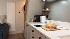 Une cuisine moderne avec un pain sur une planche à découper, une machine à café et une plante sur une étagère.