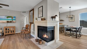 Een moderne woonkamer met een open haard, houten meubels en een eethoek.