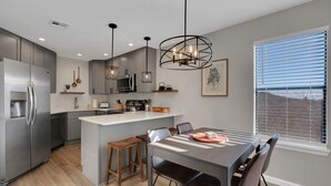 Een moderne keuken met een centraal eiland, roestvrijstalen apparatuur en hanglampen.