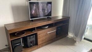 A wooden entertainment center with a flat-screen TV, a sound system, and storage drawers. - 3-bedroom apartment in wonderful João Pessoa with AC, fitness room (José Américo de Almeida João Pessoa)