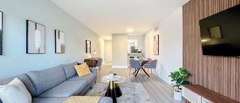 A modern living room with a grey sofa, a coffee table, and a TV mounted on the wall.