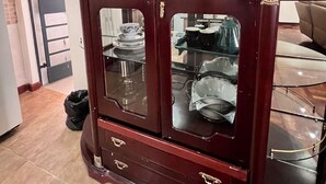 A dark wooden cabinet with glass doors and drawers, containing various dishes and glasses. - Cosy Nairobi 1bdr Apartment for Two in Westlands (Nairobi)