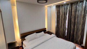 A modern bedroom with a bed, a nightstand, a blue rug, and a ceiling light fixture. - Cosy Nairobi 1bdr Apartment for Two in Westlands (Nairobi)