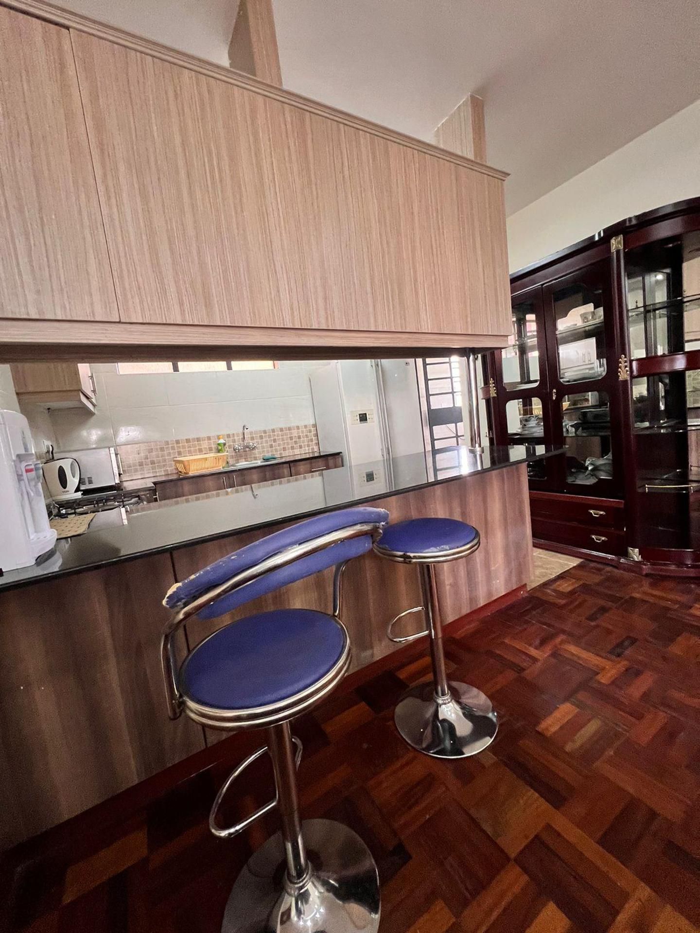A kitchen with wooden cabinets, a countertop, and a glass-fronted cabinet.