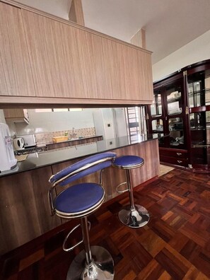 A kitchen with wooden cabinets, a countertop, and a glass-fronted cabinet. - Cosy Nairobi 1bdr Apartment for Two in Westlands (Nairobi)