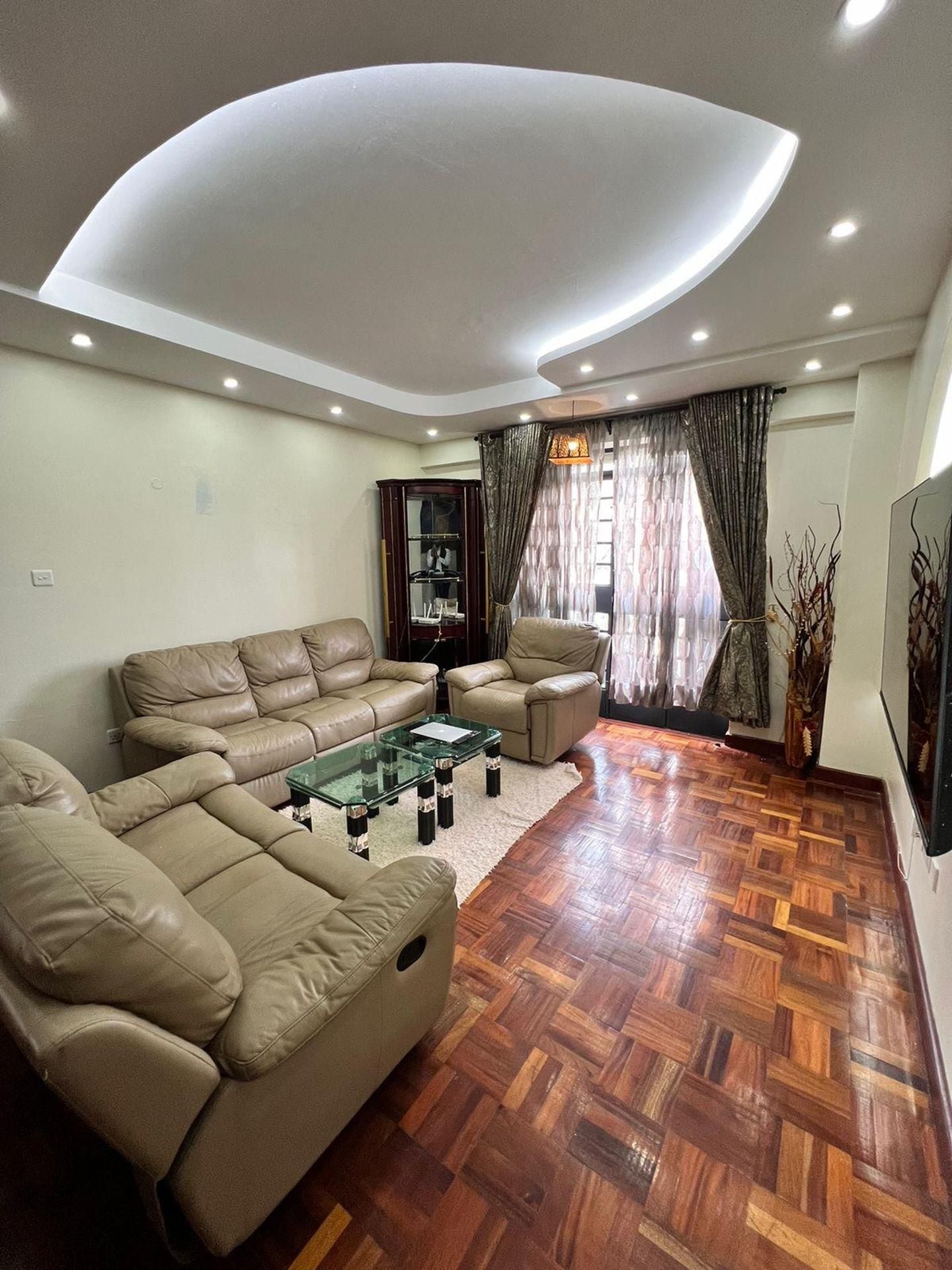 Una sala de estar con techo curvo, sofás de cuero, una mesa de centro de vidrio y un piso de parquet de madera.