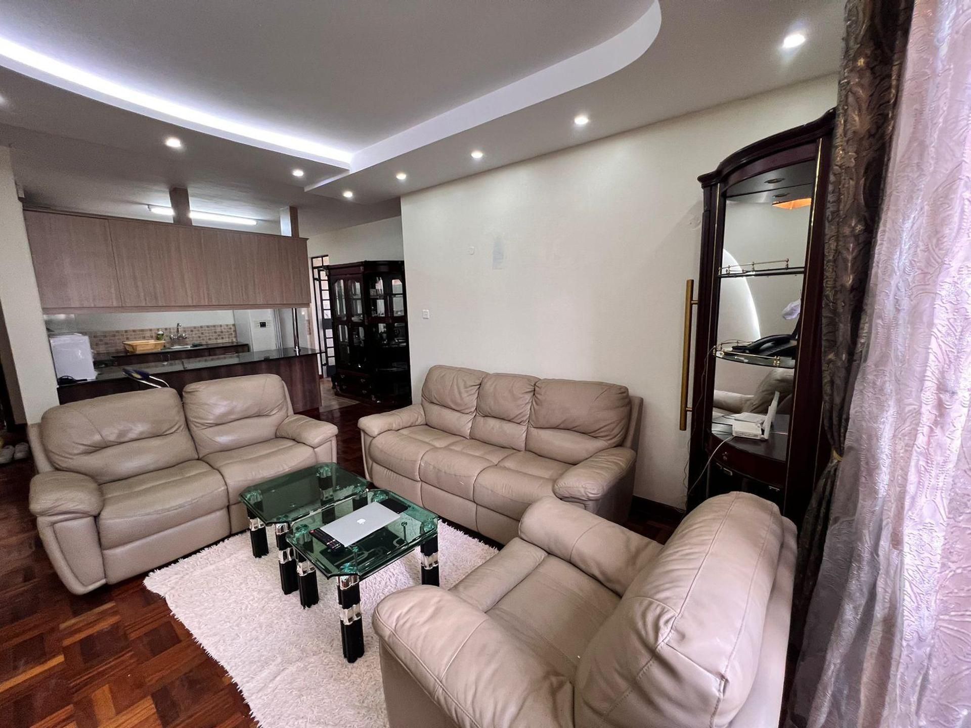 Ein Wohnzimmer mit zwei beigefarbenen Sofas, einem Glastisch und einem weißen Teppich.