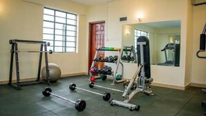 A gym with exercise equipment including a squat rack, dumbbells, a bench press, and a treadmill. - Cosy Nairobi 1bdr Apartment for Two in Westlands (Nairobi)