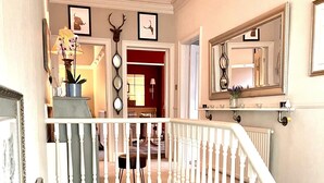 A staircase with white balusters and a handrail, leading to a landing with a framed picture and a potted plant.