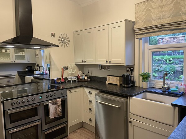 A modern kitchen with stainless steel appliances, white cabinetry, and a window with a garden view. - Seaside-scarborough-wifi-parking-petsok-sleeps-7/8 (Scarborough)