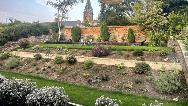 A garden with a brick wall, a tower, and a bench.