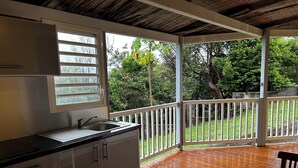 A kitchen with a window, a sink, and a view of a wooden deck and greenery outside.
