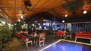 Un espace de restauration intérieur avec des tables et des bancs en bois, un bar et un sol à motifs.