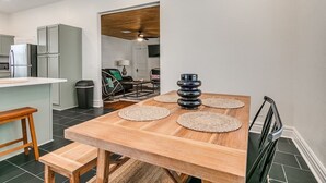 Een moderne keuken met een houten tafel, twee geweven placemats en een stapel zwarte kommen.