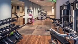 Ein Fitnessstudio mit Cardiogeräten, Gewichtsbänken und Kurzhanteln.