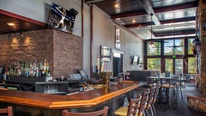Eine Bar mit Backsteinwand, Holztresen und mehreren Barhocker.