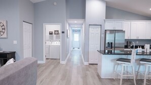 Una cocina moderna con armarios blancos, un refrigerador negro y una barra con dos taburetes.