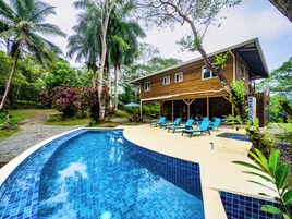 A wooden house with a pool and lounge chairs.