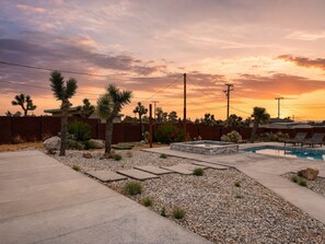 Un jardin avec une piscine, des palmiers et un hamac.