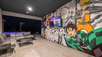 Een moderne woonkamer met een grote televisie, een bank en een wanddecoratie met anime personages.