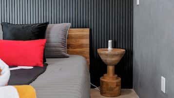 Une chambre à coucher avec un lit, des oreillers, une table de chevet et un climatiseur fixé au mur.