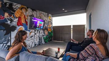 Een kamer met een grote televisie, een muurschildering en een bank.