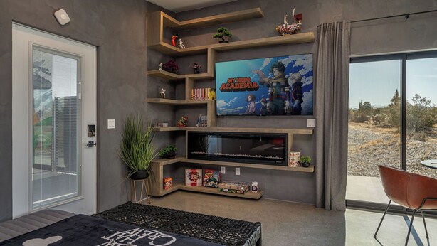A modern living room with a large flat-screen TV, built-in shelves, and a comfortable seating area. - Saltwater Pool/Sauna/Mini Golf/JT Nat Park/Firepit (Yucca Valley)