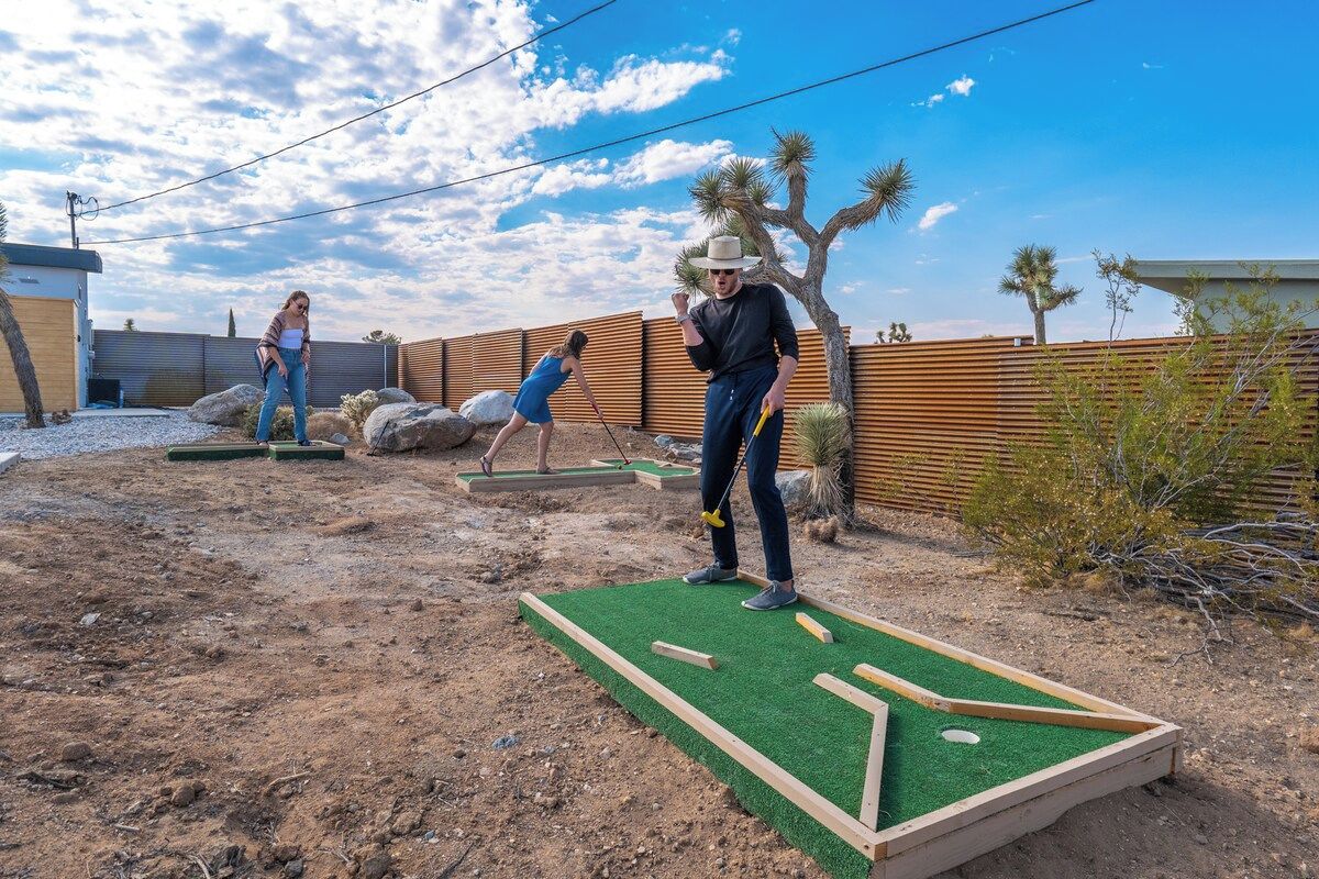 Un jardin avec un terrain de mini-golf, une clôture en bois et un paysage désertique.