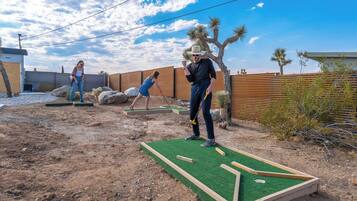 Un jardin avec un terrain de mini-golf, une clôture en bois et un paysage désertique.