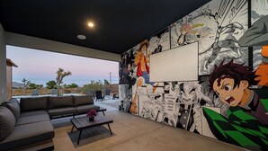 A modern living room with a large mural, a sofa, a coffee table, and a view of the outdoors. - Saltwater Pool/Sauna/Mini Golf/JT Nat Park/Firepit (Yucca Valley)