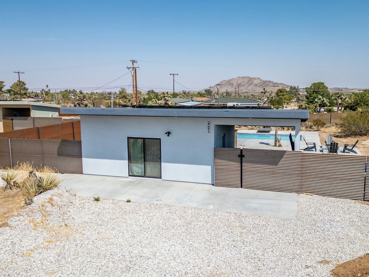 Une maison moderne dotée d’une piscine, d’un patio clôturé et offrant, en arrière-plan, un paysage désertique.