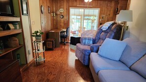 Ein gemütliches Wohnzimmer mit einem blauen Sofa, Holzböden und einem Essbereich mit Tisch und Stühlen.