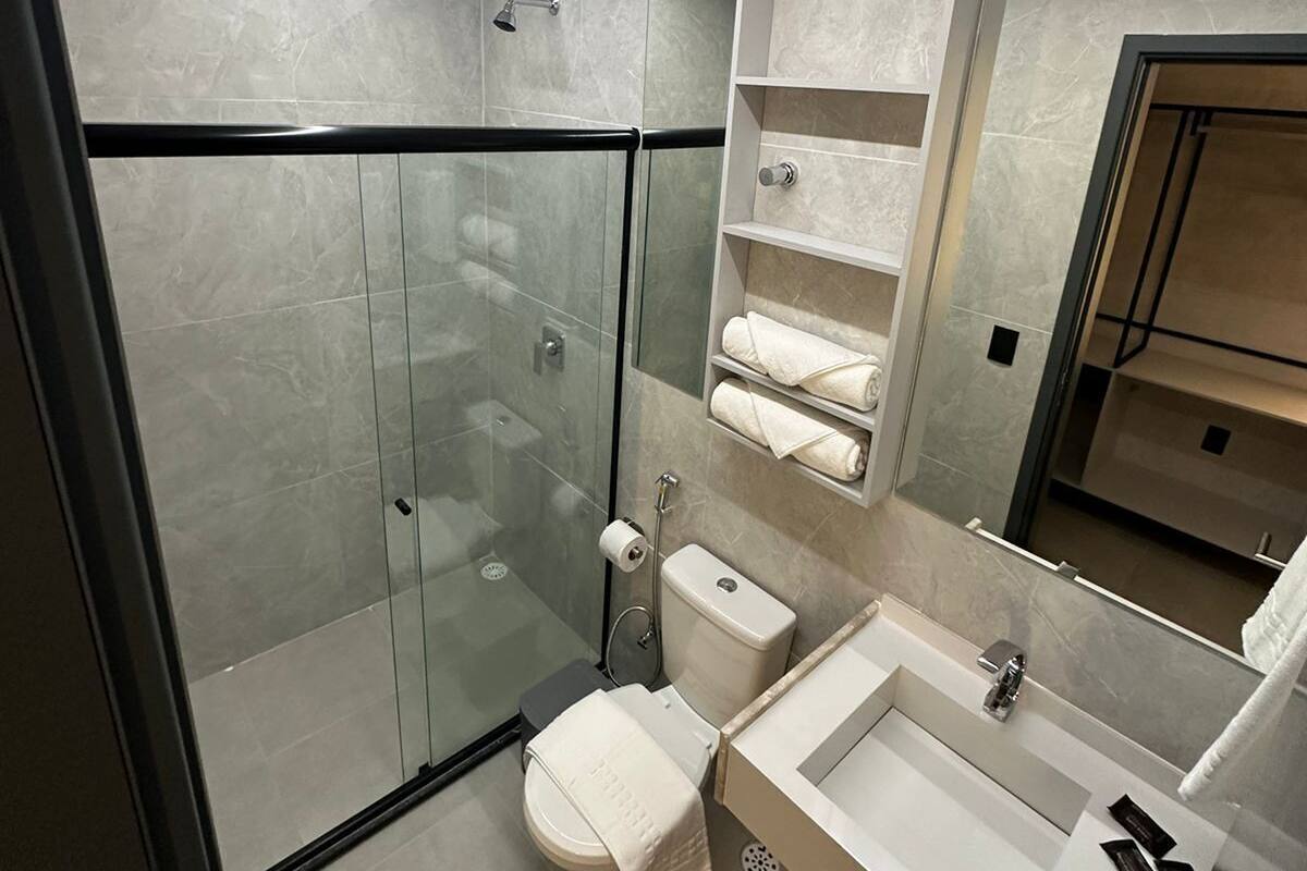 Une salle de bain moderne avec une douche à parois de verre, des toilettes et un lavabo avec un miroir au-dessus.