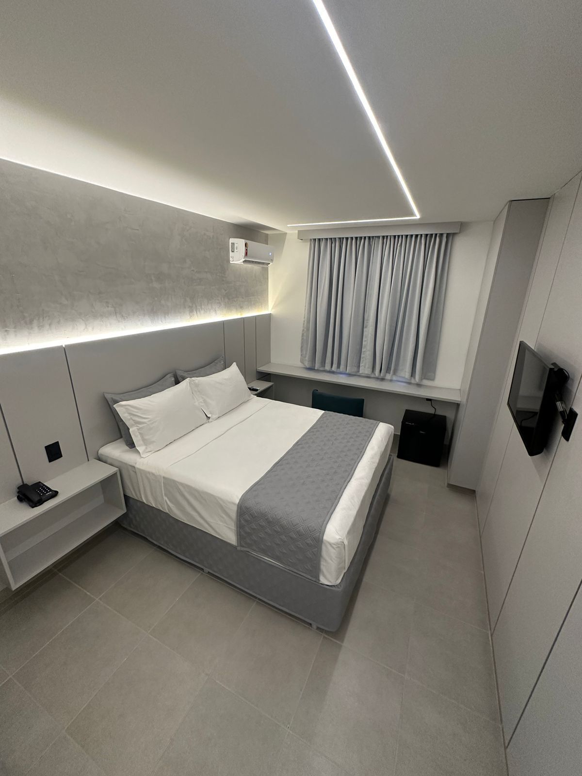 Une chambre d’hôtel moderne équipée d’un lit, d’une table de chevet et d’un téléviseur.