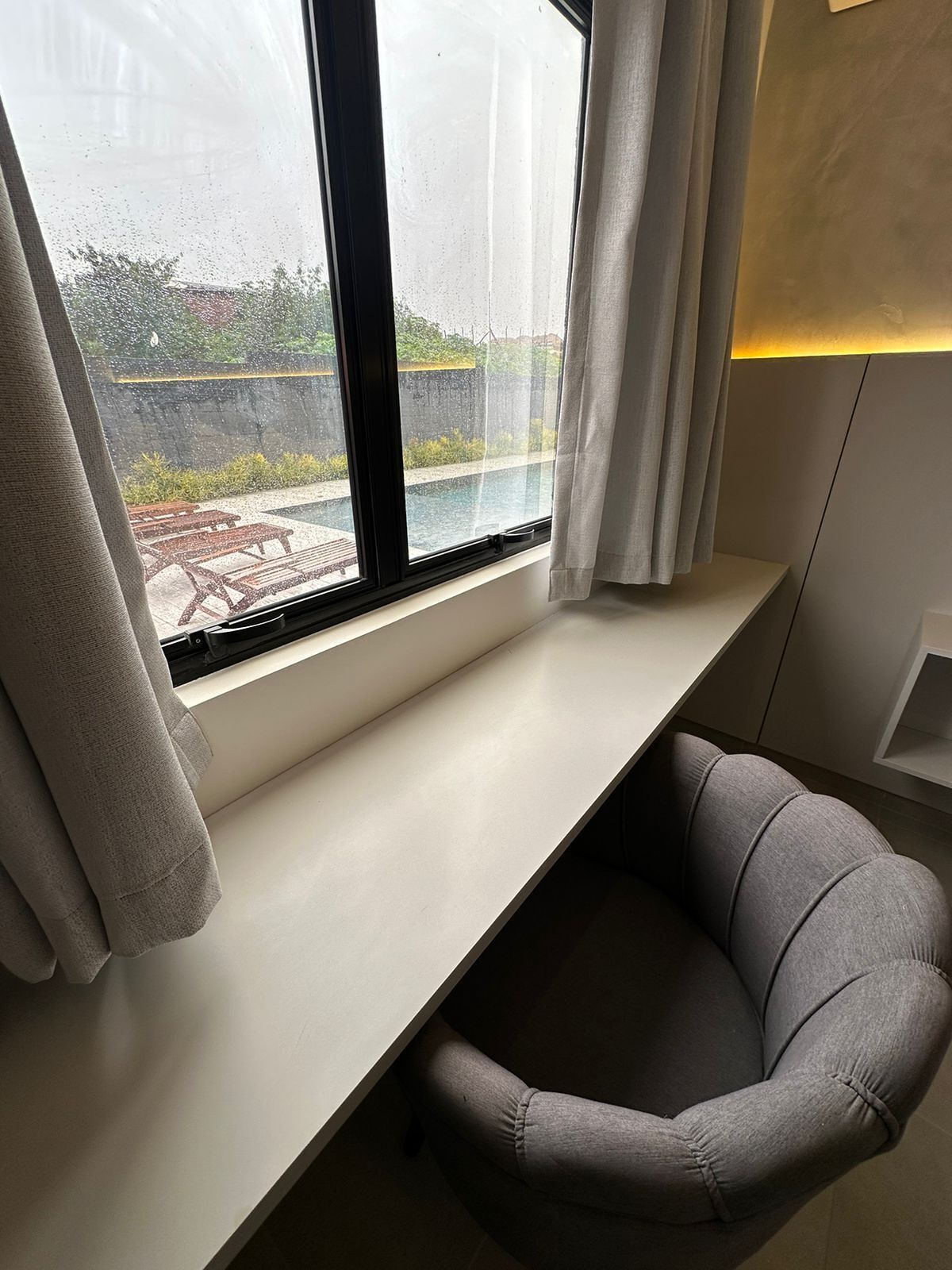 A modern room with a window overlooking a pool and garden.
