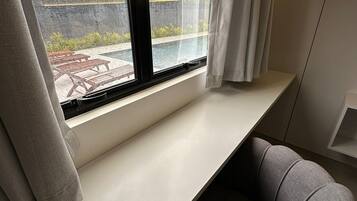 Quarto moderno com janela vista para piscina e jardim.
