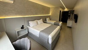 Une chambre d’hôtel moderne avec un grand lit, des tables de chevet, une chaise et un téléviseur intégré.