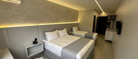 Habitación de hotel moderna con una cama grande, mesitas de noche, una silla y televisión integrada.