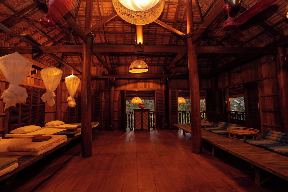 Interior de madera con varias camas y una mesa central.