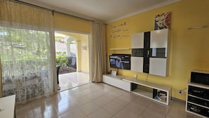 A living room with a TV, a white entertainment unit, and a yellow wall with motivational quotes. - 1 Bed Apt Sleeps 5 - Indoor Pool - Free Parking (San Miguel de Abona)