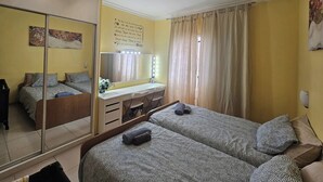 A bedroom with two beds, a mirror, a vanity with lights, and a yellow wall. - 1 Bed Apt Sleeps 5 - Indoor Pool - Free Parking (San Miguel de Abona)