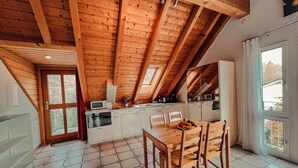 Eine moderne Küche mit Holzbalken, einer Essecke mit sechseckigen Fliesen und einem großen Fenster.