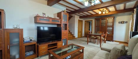 A living room with a TV, wooden cabinets, a glass coffee table, and a sofa.